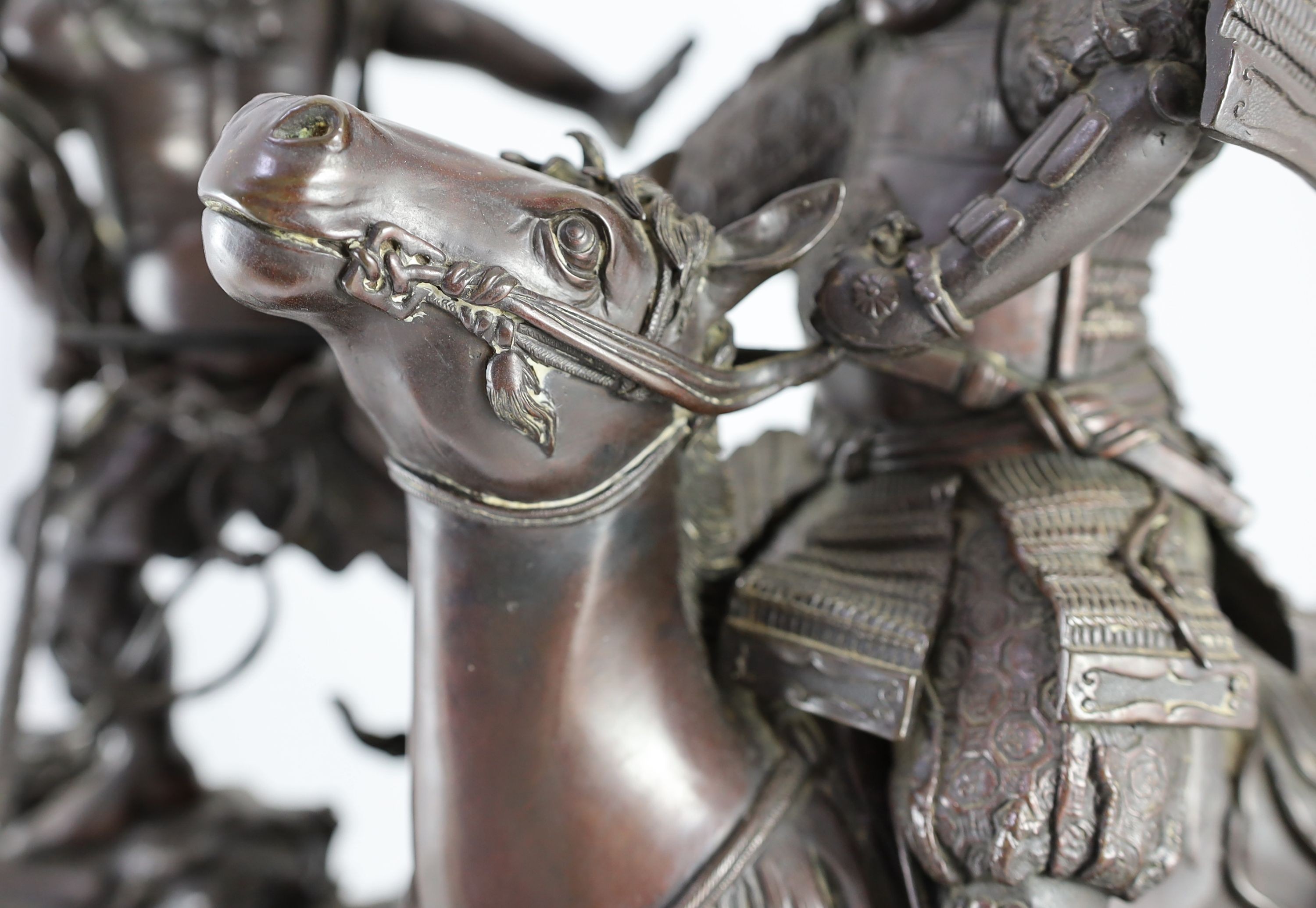 An impressive Japanese bronze group of an oni attacking a Samurai on horseback, Meiji period, 58cm high 49.5cm wide